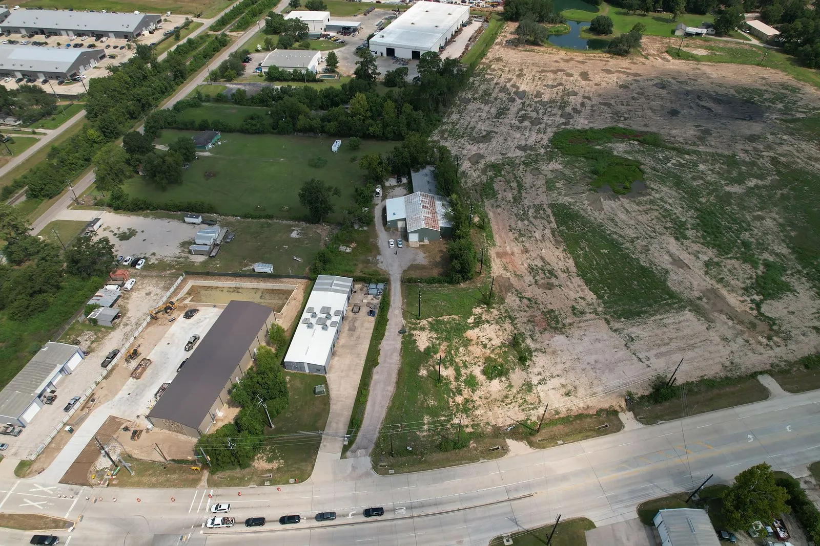Drone aerial of industrial buildings and open land along a Houston-area road