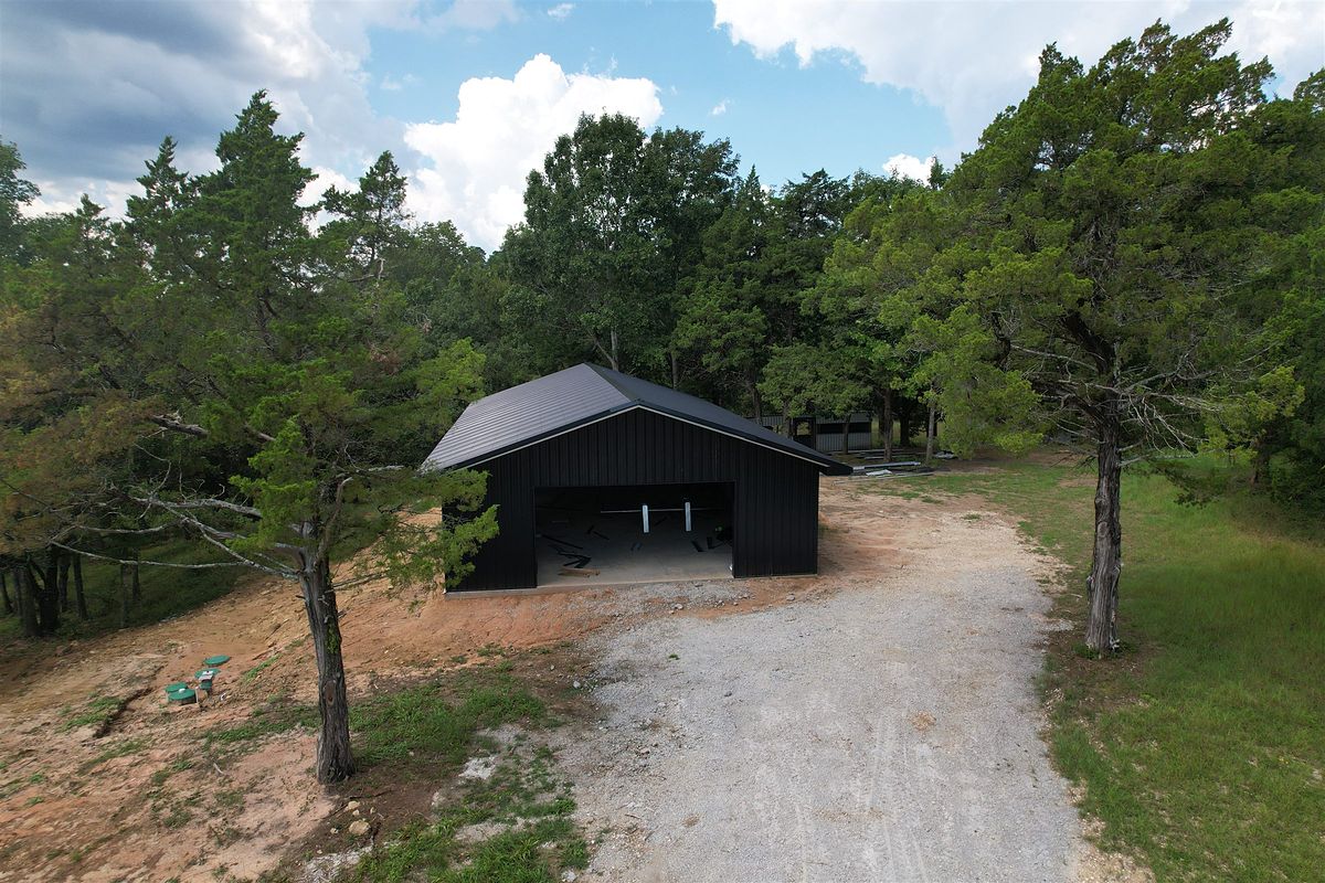 Gravel drive through pines to a steel building in Coldspring, Texas